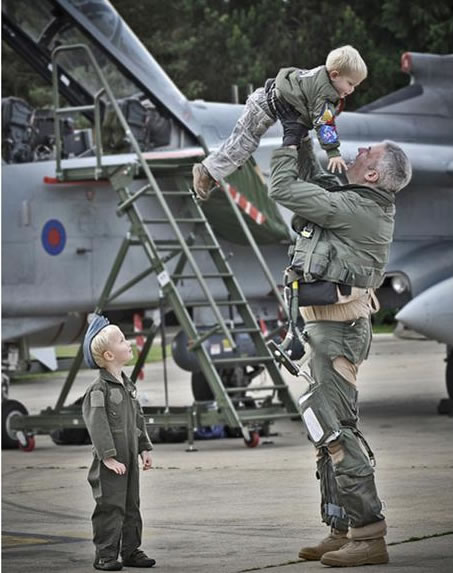 WG CDR Turk and his children...part of the winning entry from RAF Marham Category A 'Photographic Section Portfolio' sponsored by Canaon UK. 'Welcome Home' by SAC Chris Hill. IMAGE OF OC 9 SQN, WG CDR TURK, LIFTING HIS CHILD IN THE AIR WHILST HIS OTHER CHILD LOOKS UP WAITING FOR HIS TURN. TAKEN ON 9 SQN'S TORNADO'S RETURN TO RAF MARHAM FROM OPERATION ELLAMY.