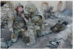 Image of Lance Corporal Simon Moloney (left), The Blues and Royals, in Afghanistan. Seen here receiving medical attention from LCpl Wesley Masters, Royal Army Medical Corps, after being shot in the neck whilst on Op. Source: MoD